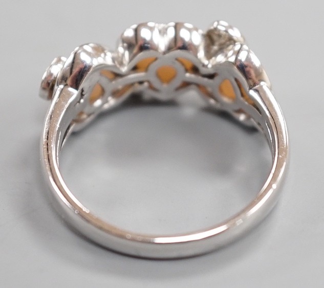 A modern 750 white metal three stone heart shaped mother of pearl? and diamond chip cluster set half hoop ring, signed Damas, size Q, gross weight 5.4 grams.